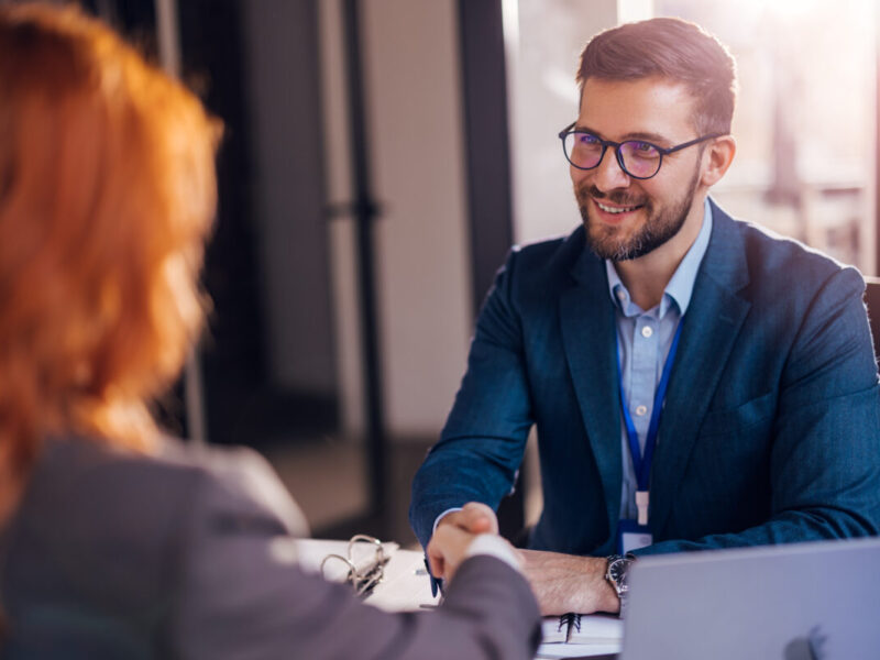 Happy bank manager shaking hands with a client after successful agreement in the office.